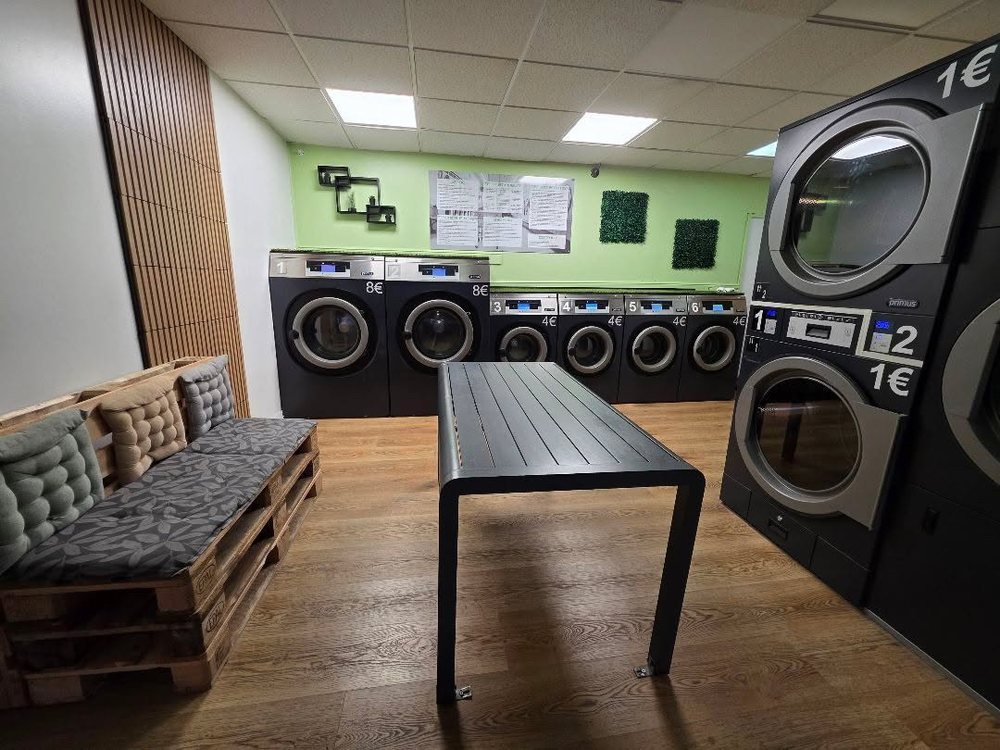 L'intérieur de la Laverie Magudas : 6 machines à laver et une grande table
